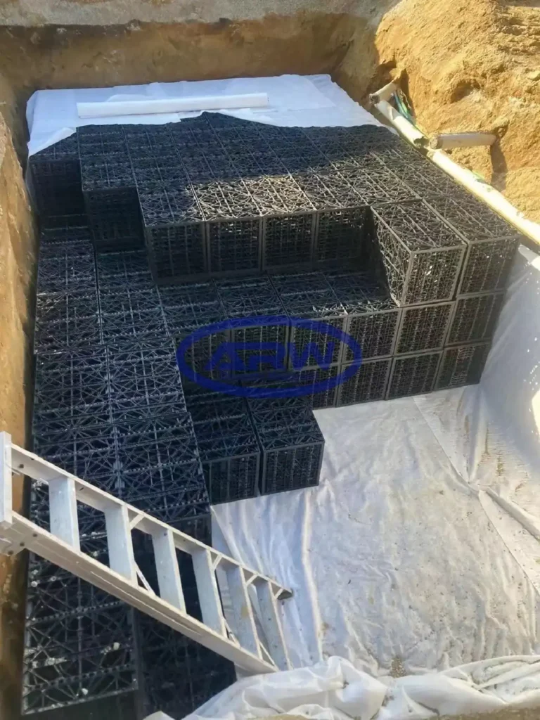 Ouvrage résidentiel de rétention sur site (OSD) en Australie et en Nouvelle-Zélande : modules alvéolaires de stockage posés sur un géotextile non tissé blanc ; des conduites latérales raccordent l’ouvrage pour la régulation du débit et l’infiltration.